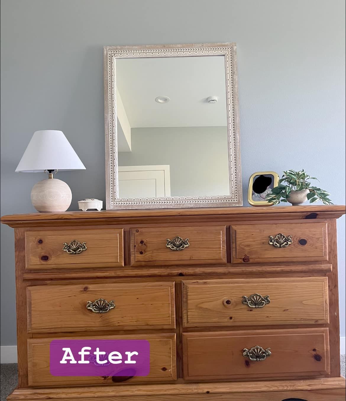 A wooden dresser with drawers and a mirror in a bedroom.