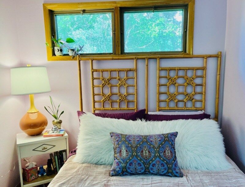 A bedroom with a bed , nightstand , lamp and window