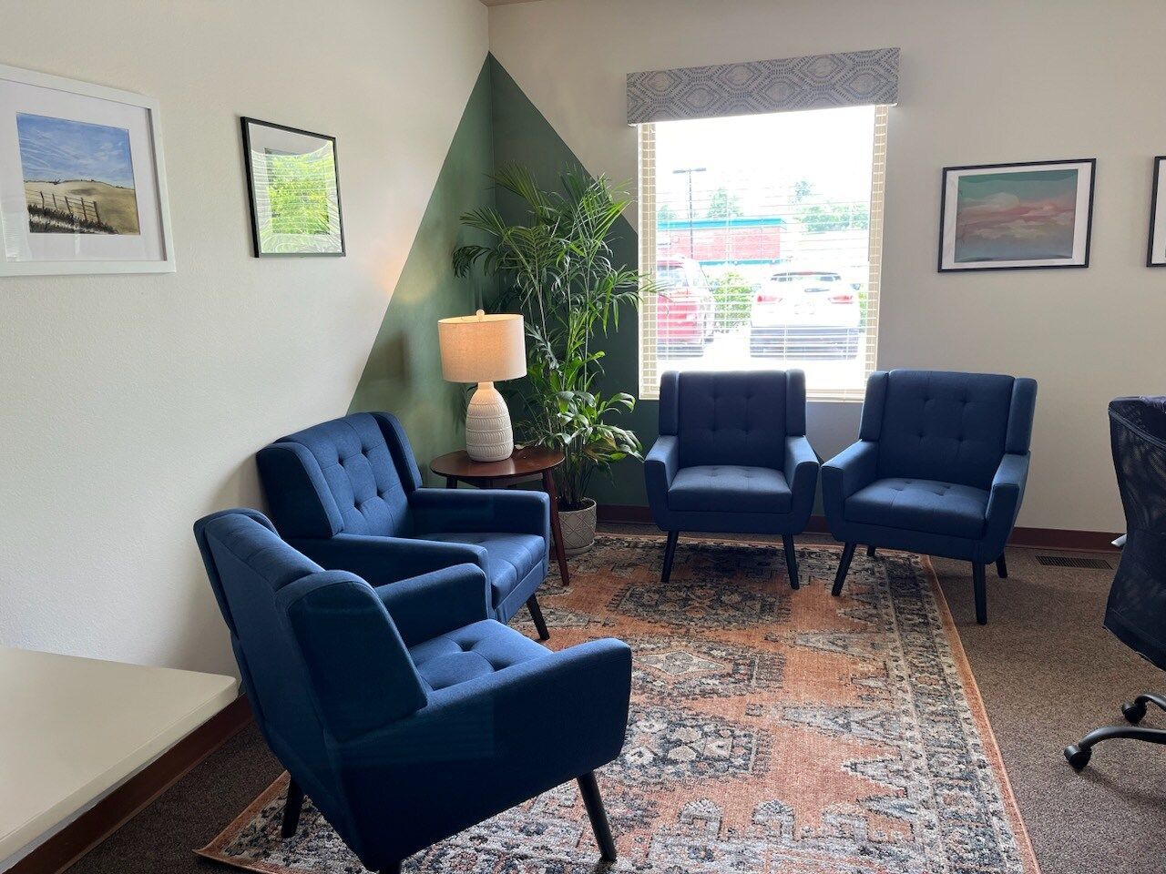 A waiting room with blue chairs and a window.