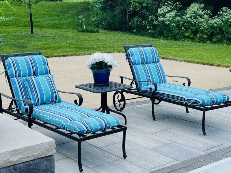 Two lounge chairs with blue cushions are sitting next to each other on a patio.