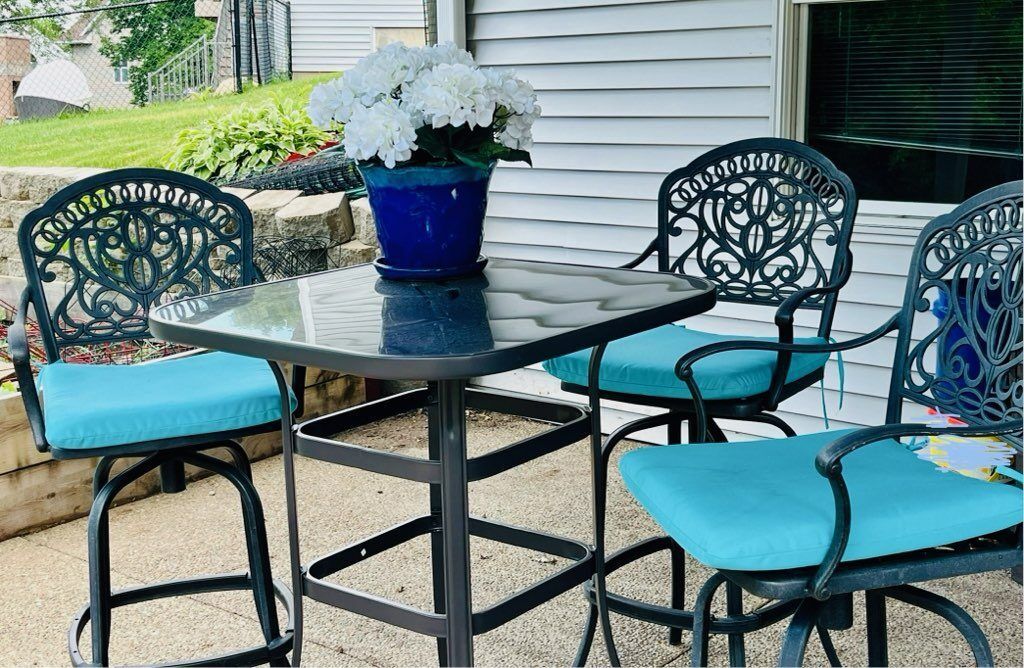 A table and chairs on a patio with a potted plant on the table.