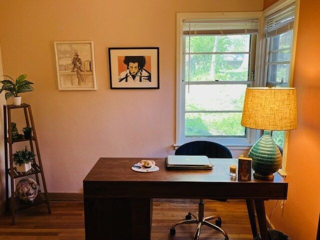 A desk with a laptop on it in a room with a lamp.