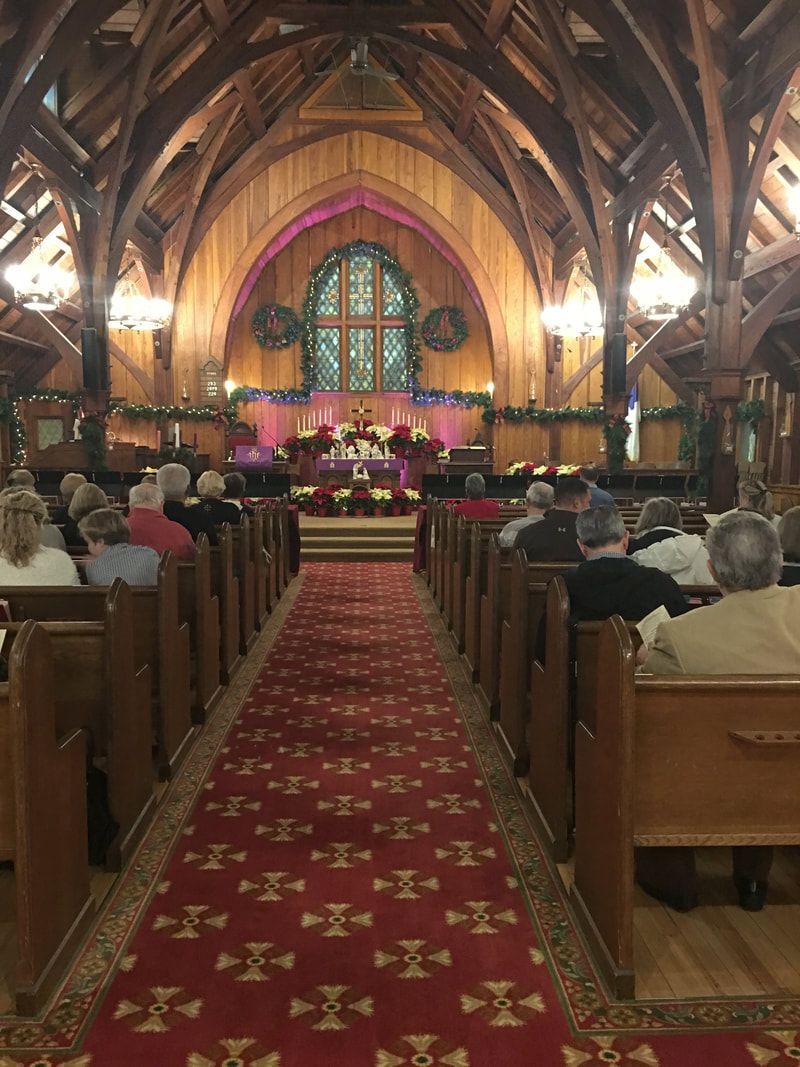 A church with people sitting in the pews and a red carpet