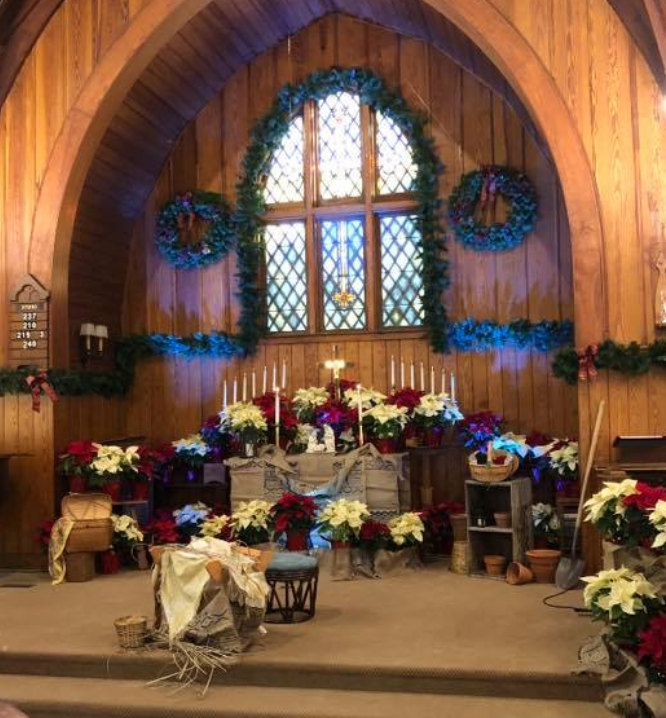 A church is decorated for christmas with flowers and candles