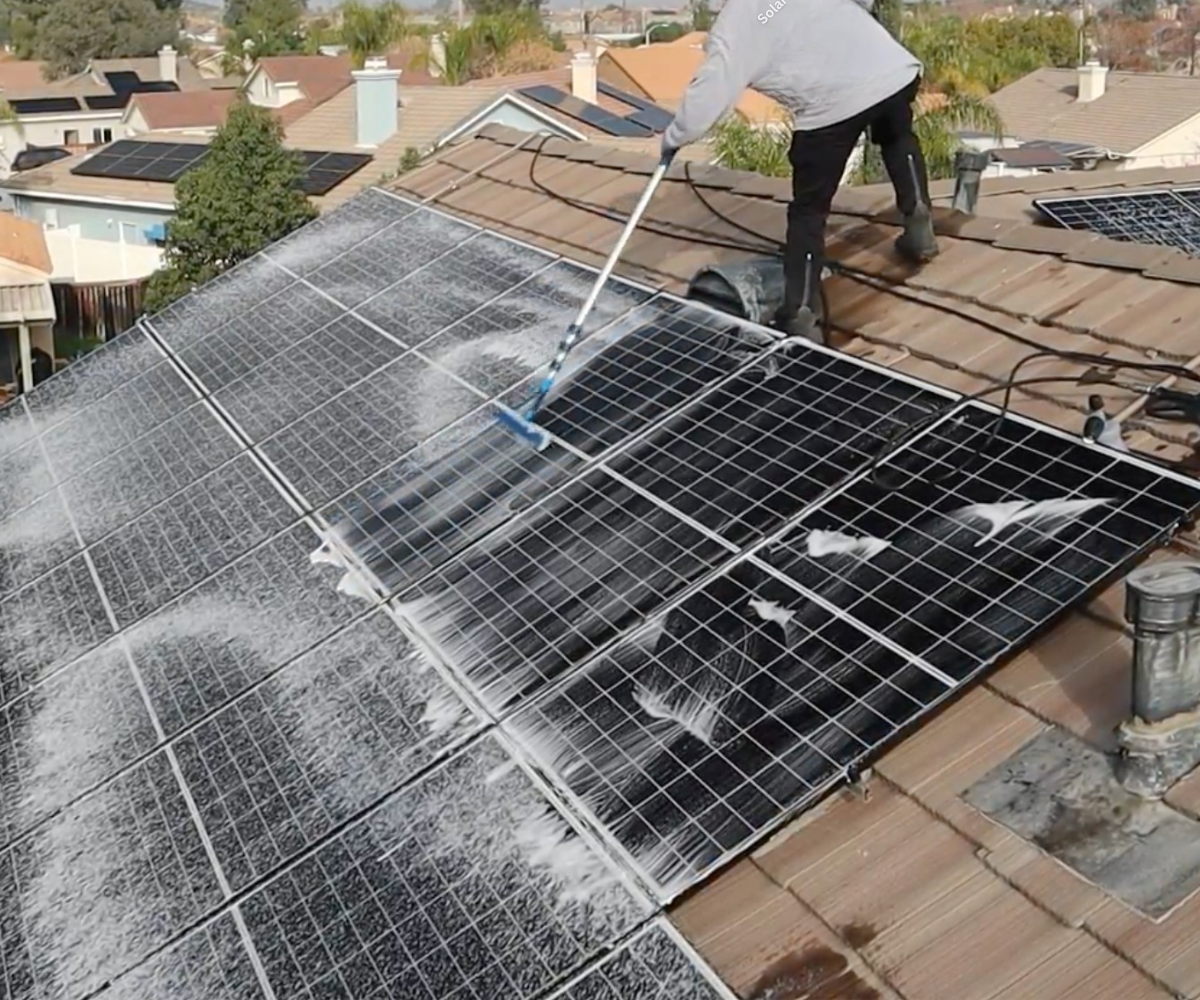 Technician cleaning rooftop solar panels on a Utah County home