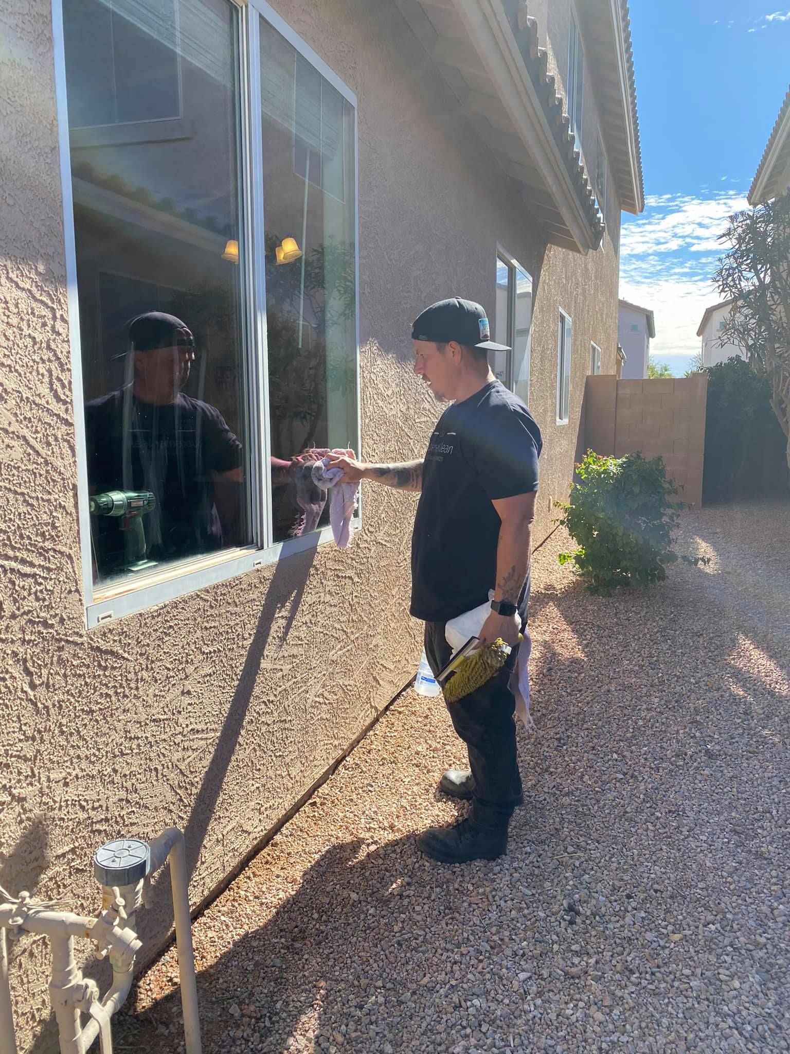Window being washed with a long handled brush. Yellow and black brush on a window of a light colored building.