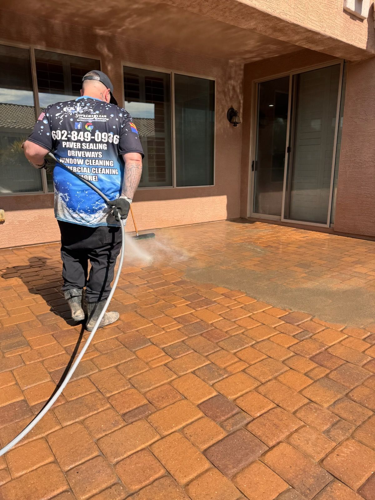 Man pressure washing a brick patio; cleaning the bricks; outside.