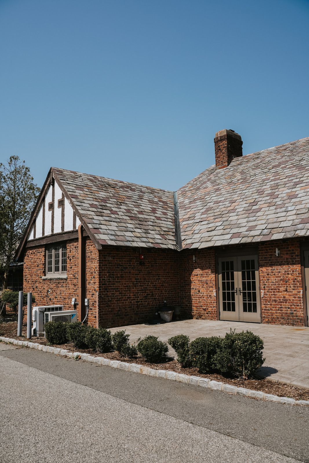 Red brick building with gray roof, white accents, and a clear blue sky.
