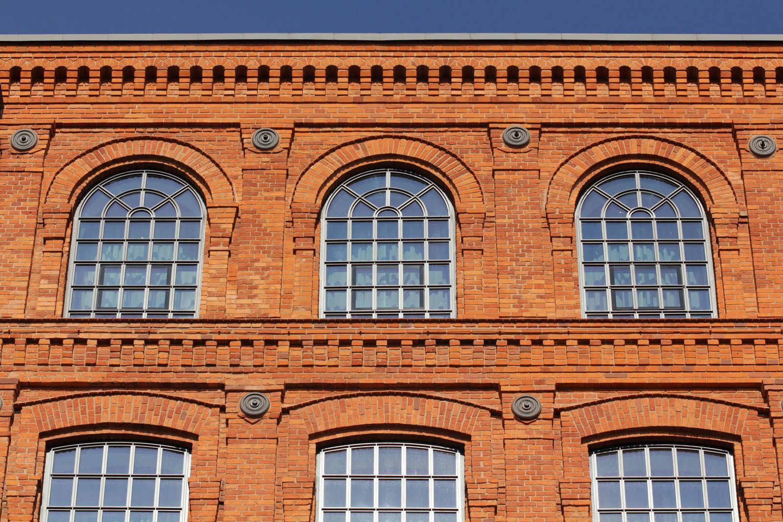 Red brick building with arched windows and decorative detailing.