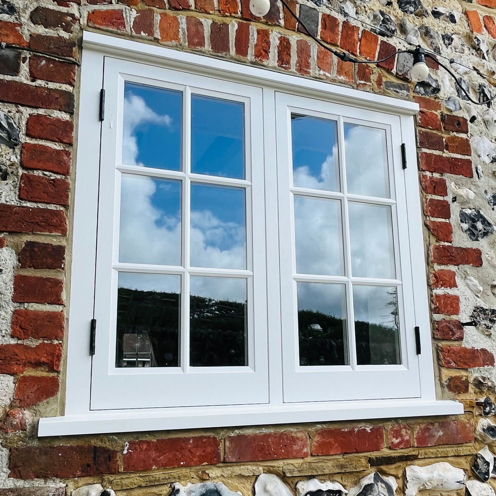 Double casement windows with white frame in a brick house