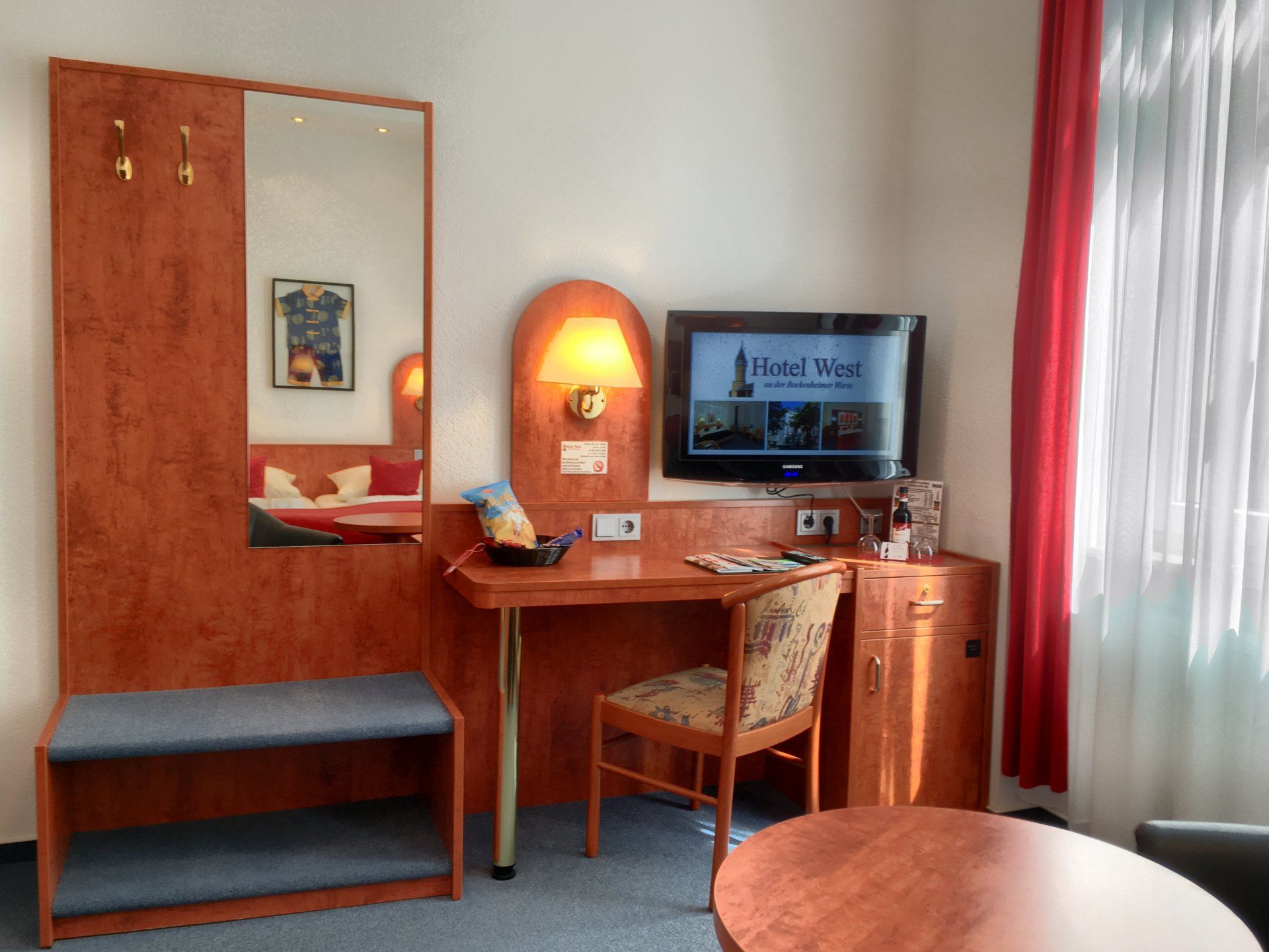 A hotel room with a desk a chair and a flat screen tv