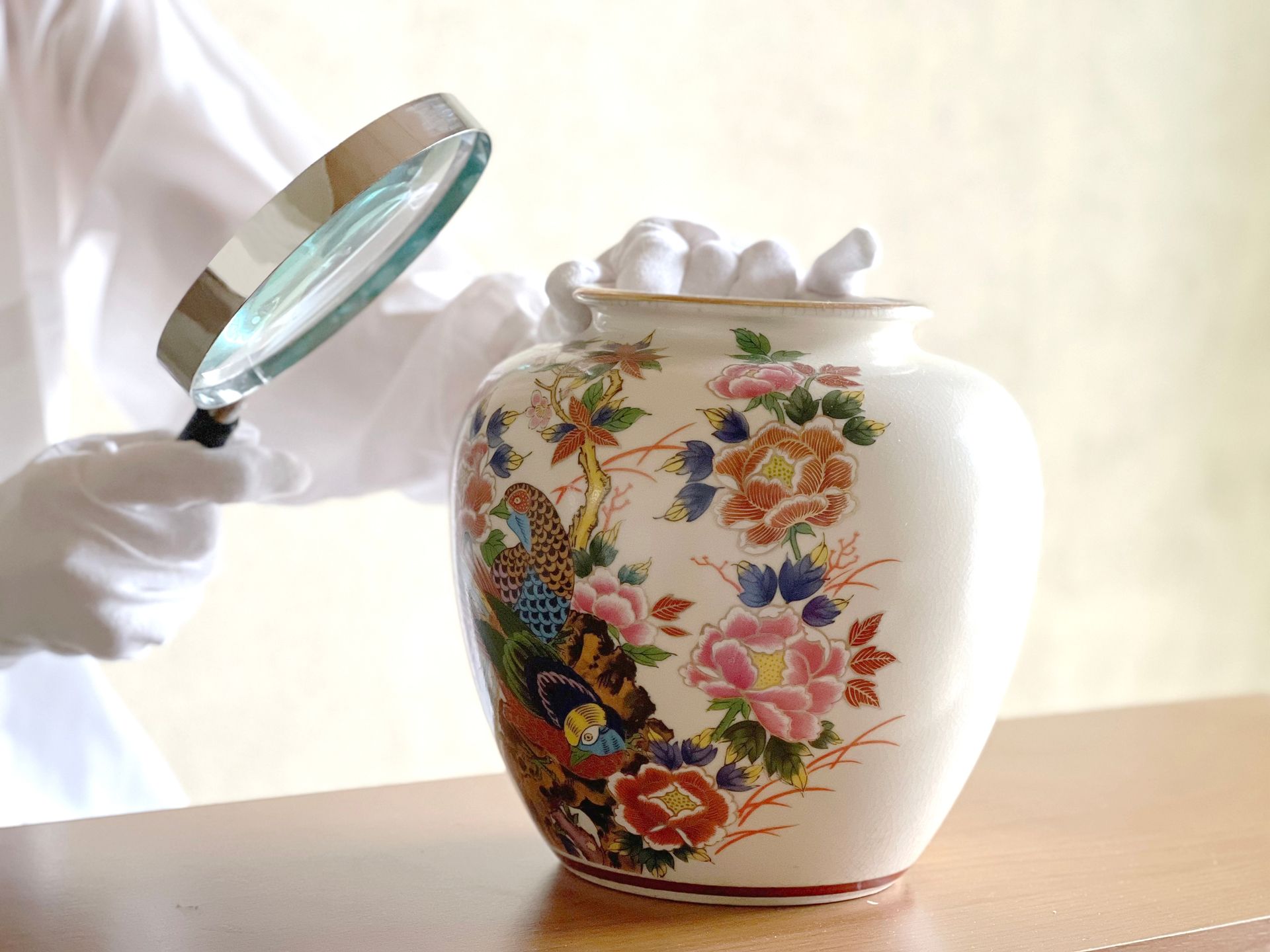 A Person is Looking at a Vase With a Magnifying Glass