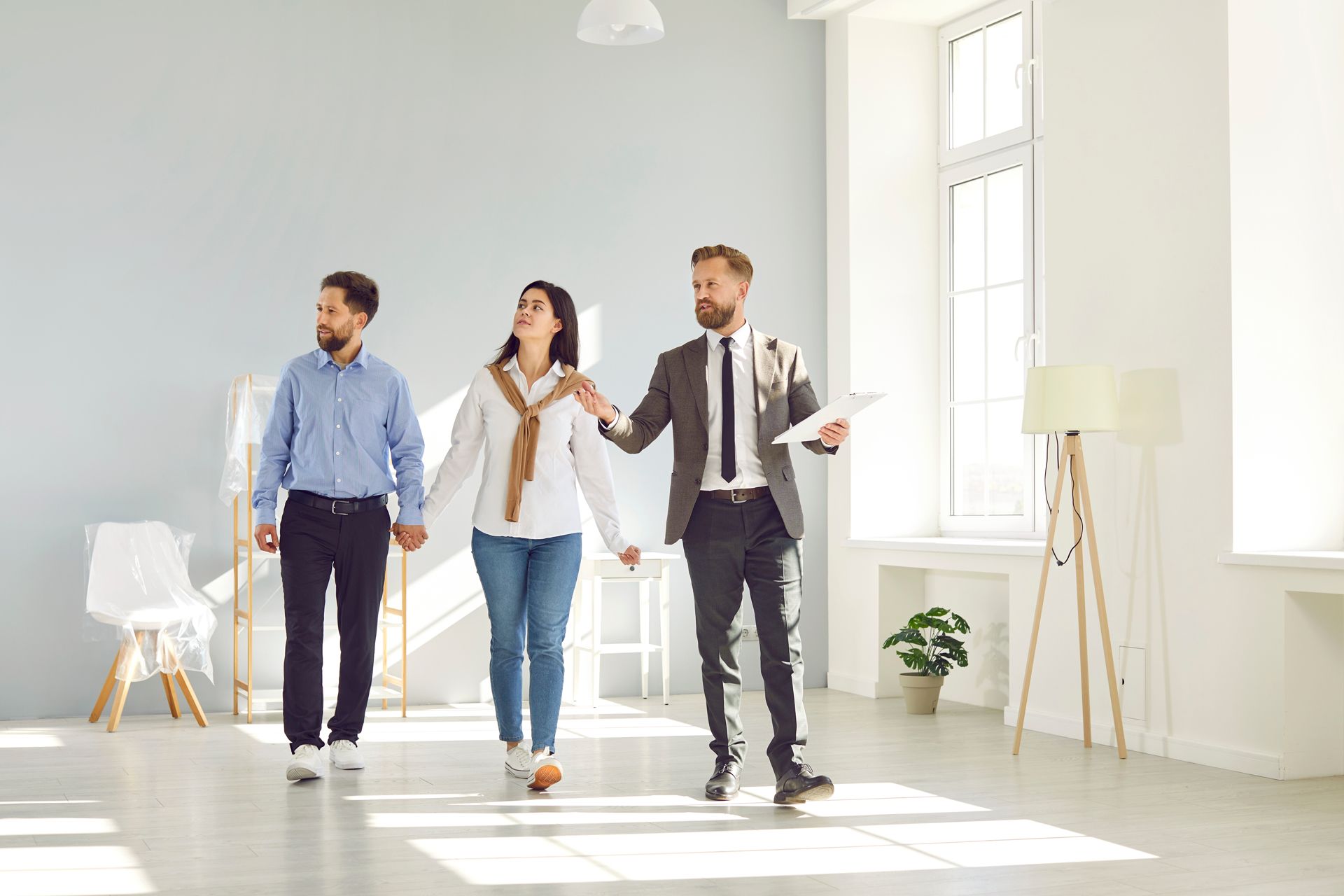 A Man and a Woman Are Walking Through an Empty Room With a Real Estate Agent