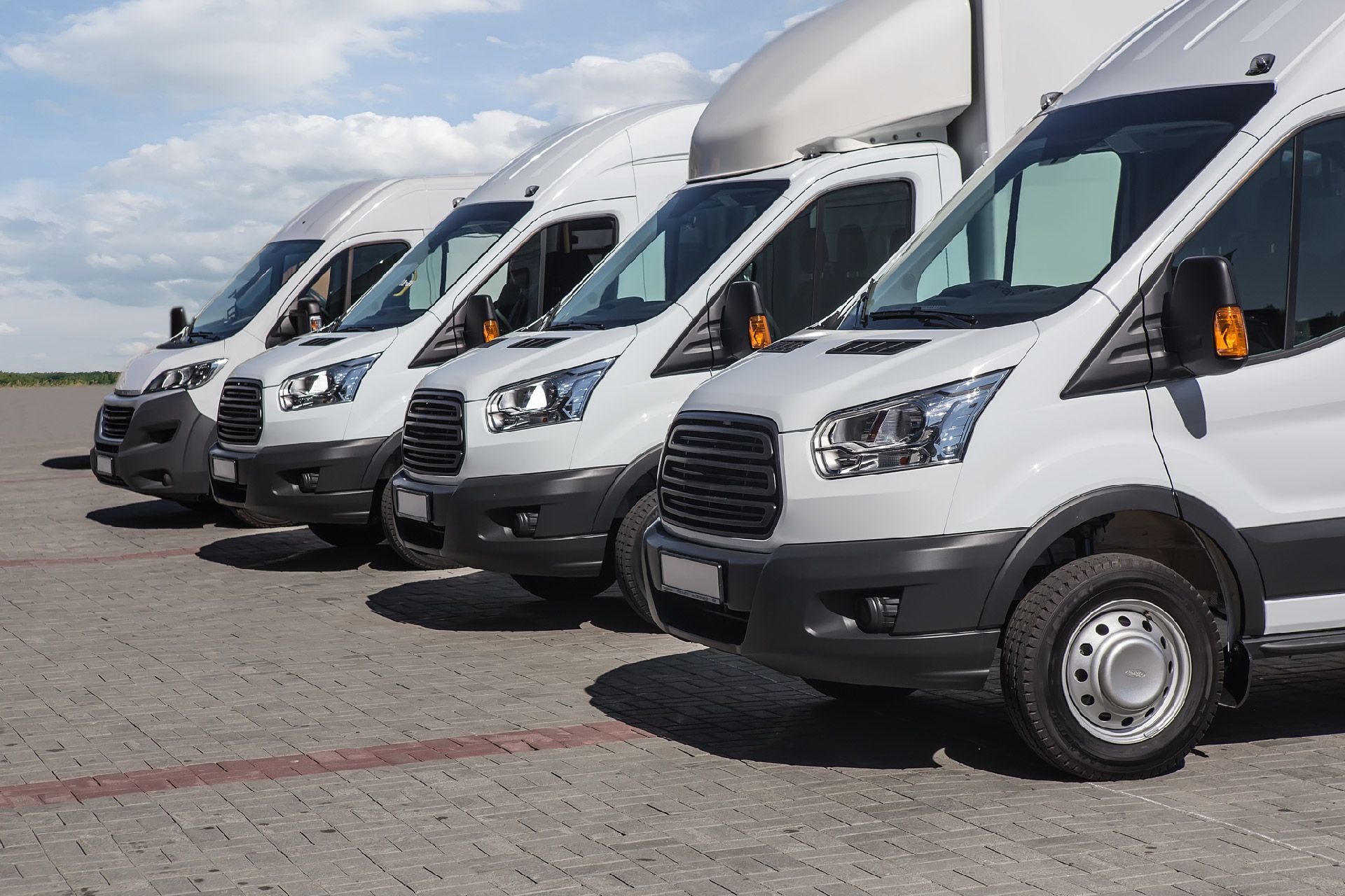 Una fila de furgonetas blancas están estacionadas en un estacionamiento.