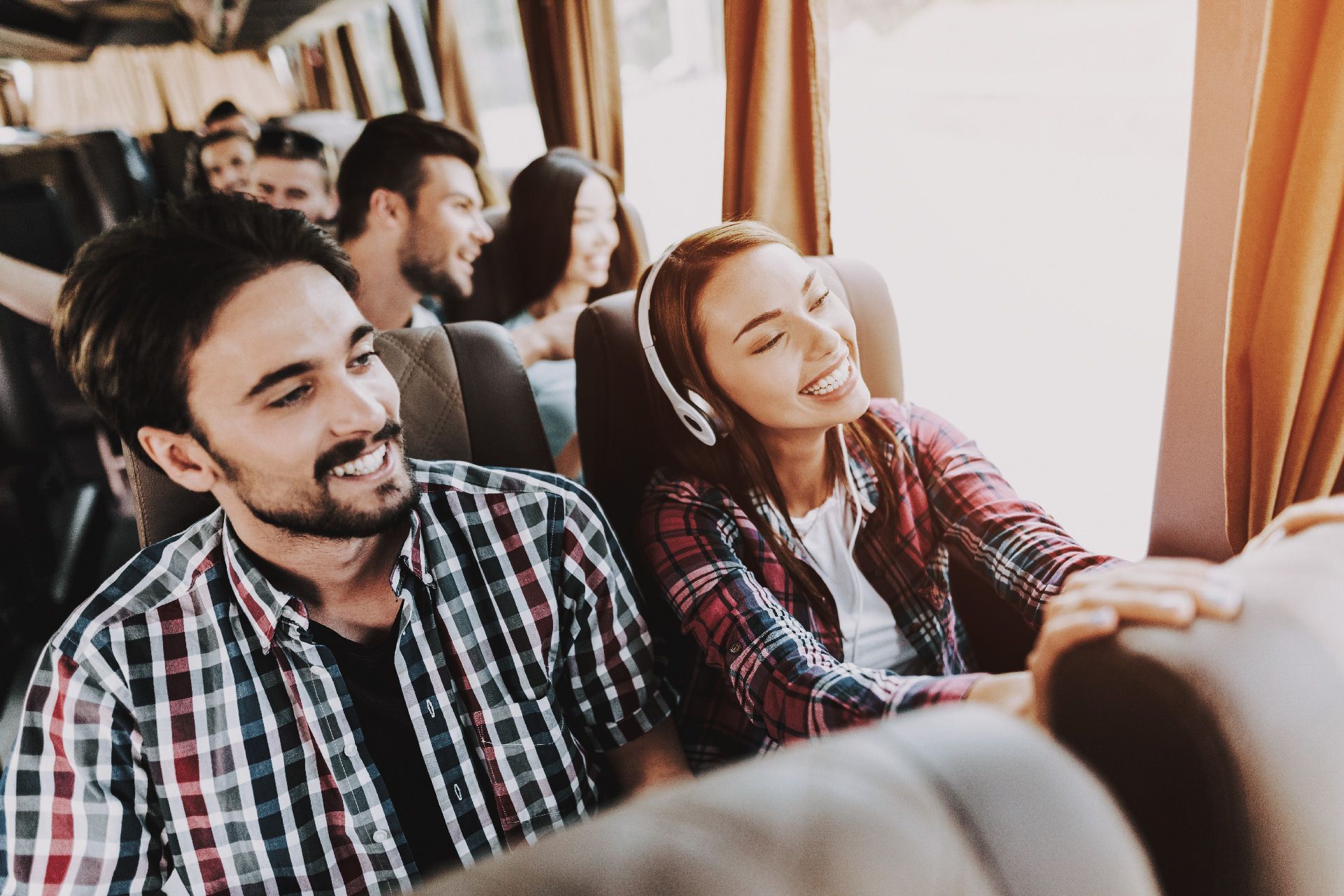 Un hombre y una mujer están sentados en un autobús con auriculares.
