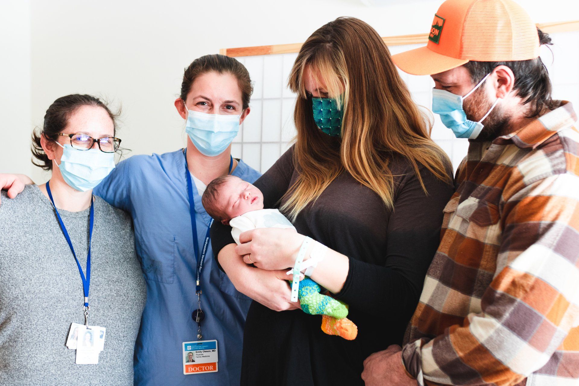 A mom and dad with two staff members and the newest member of their family