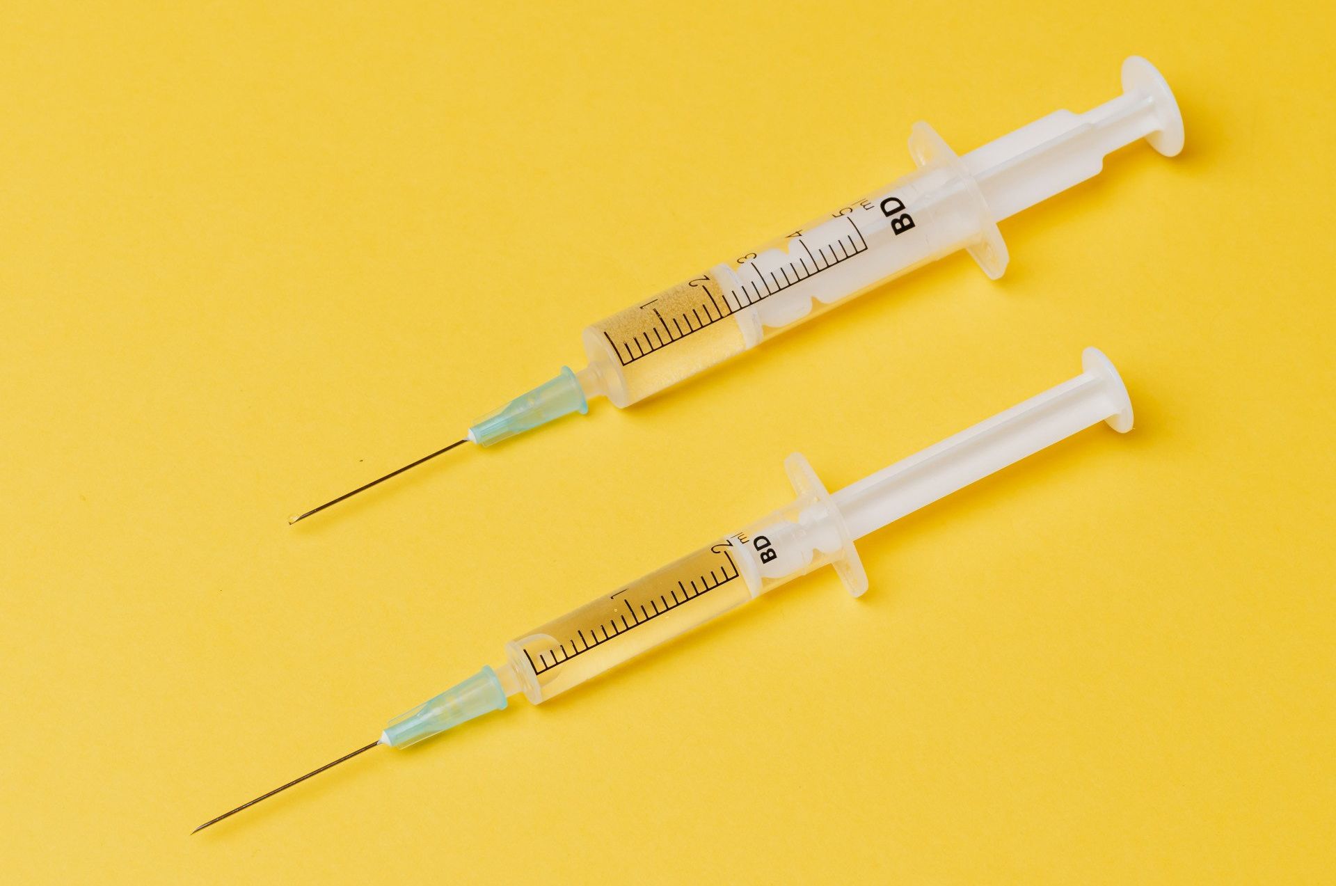 Two full vaccines lie on a yellow background