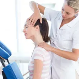 Chiropractor adjusting a patient’s neck in a bright clinic, with a treatment table nearby