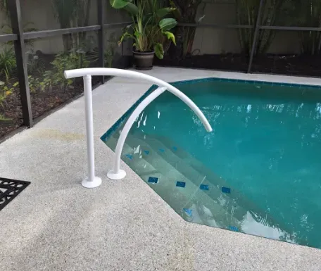 White pool handrail beside pool steps.