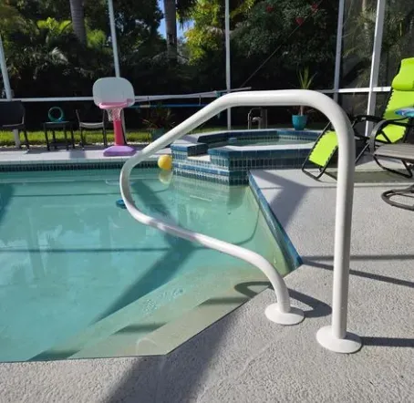 White handrail at the edge of a swimming pool with a spa, sunny outdoor setting.