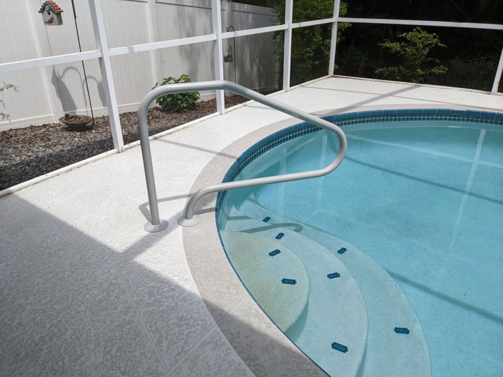 Pool with curved steps, a railing, and a screened enclosure.