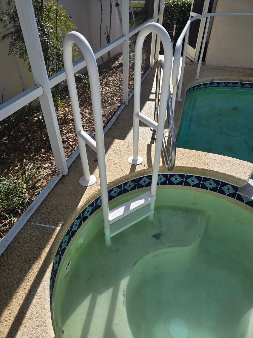 White pool ladder descending into a circular pool with blue-tiled edge, next to white screened patio.