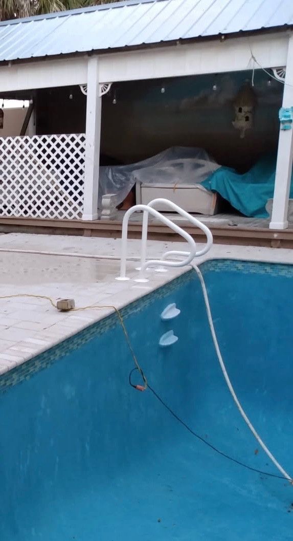 Empty pool with white handrails, blue interior, and gazebo in the background.
