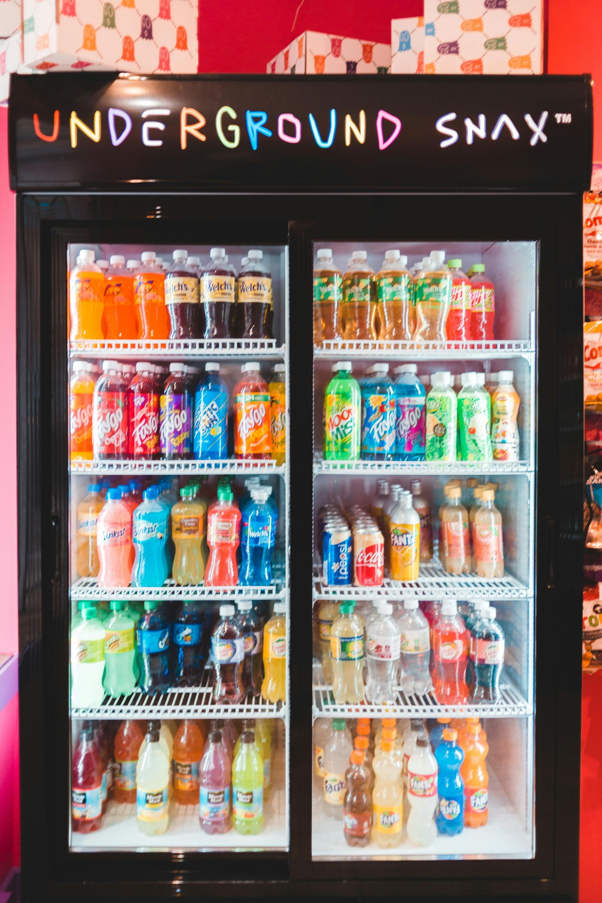 Refrigerator stocked with colorful bottled drinks, labeled