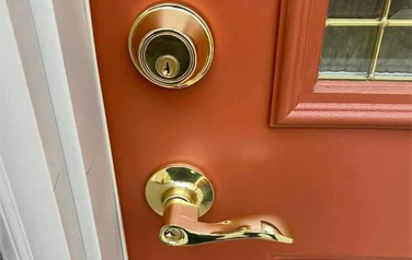 A close up of a door with a gold handle and lock