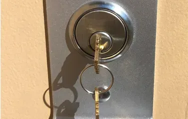 A close up of a door lock with two keys in it.