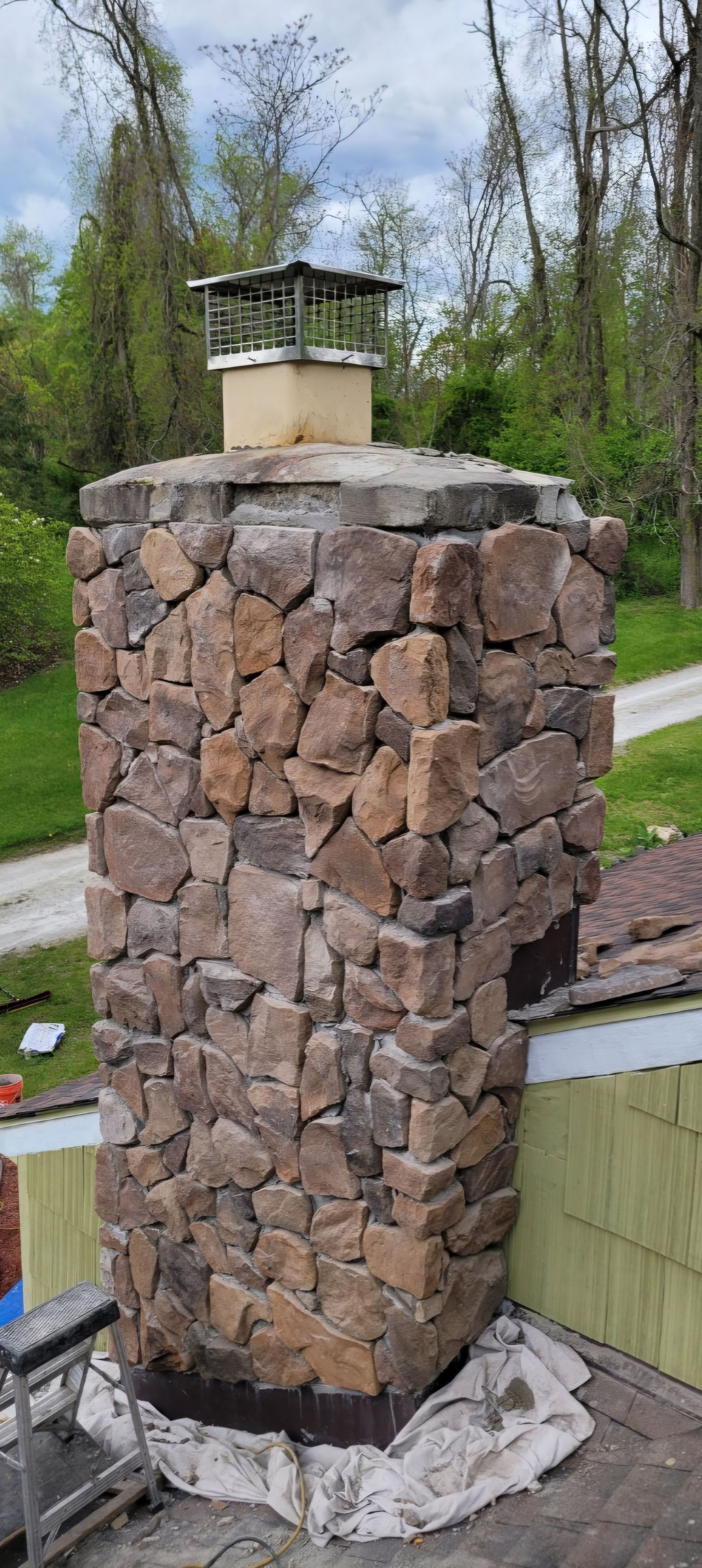 A stone chimney is sitting on top of a patio next to a road.