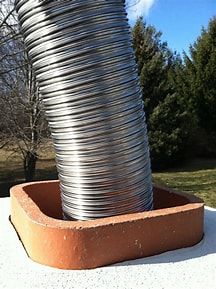 A metal hose is sitting on top of a brick chimney.