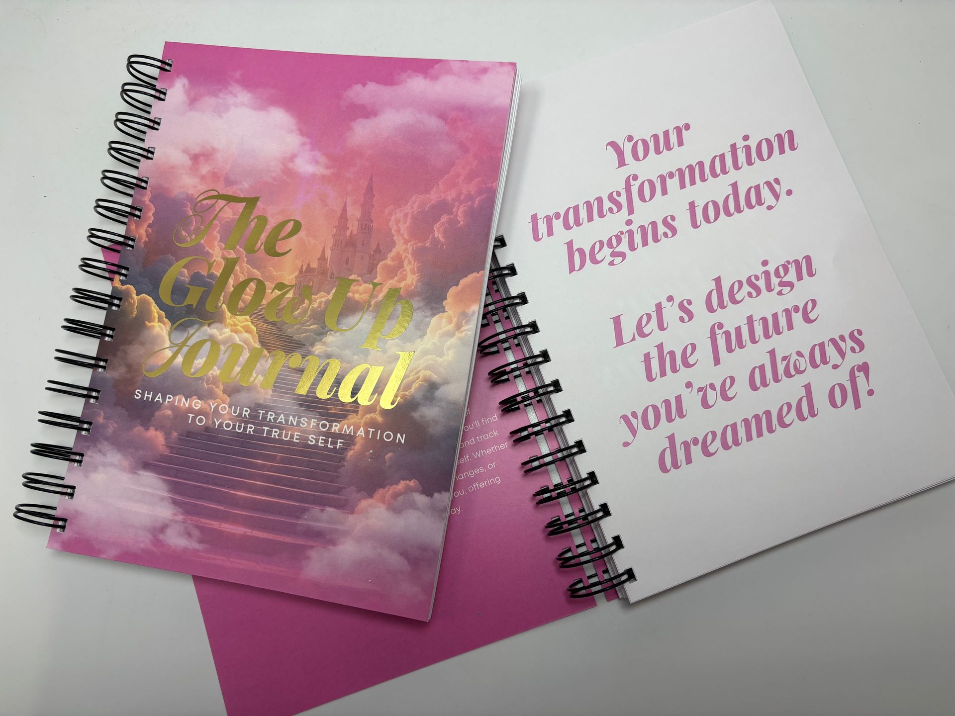A pink spiral bound notebook with the words