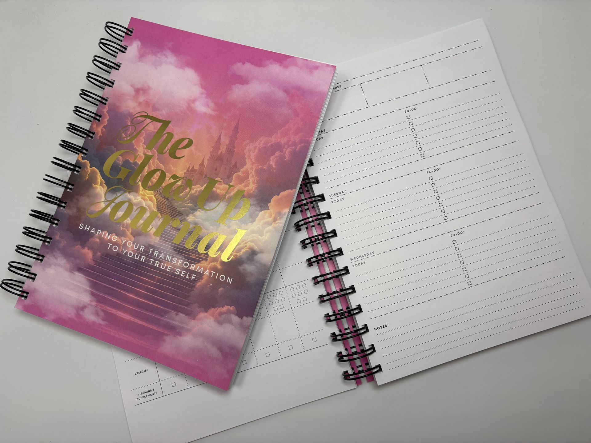 A spiral notebook with a pink cover is sitting on a table.