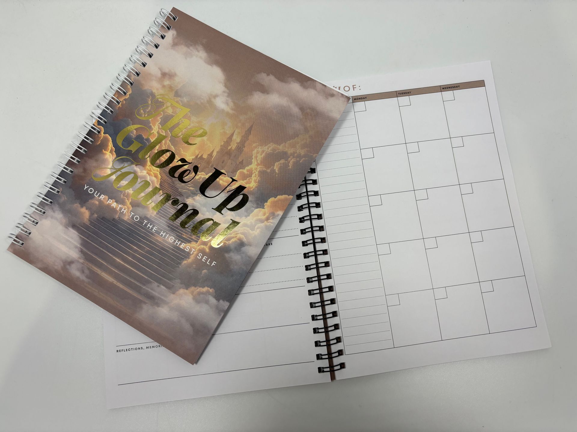 A spiral notebook with a picture of a cloudy sky on it.