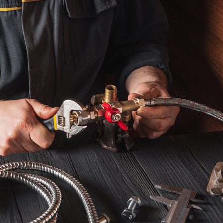 A man is working on a pipe with a wrench.