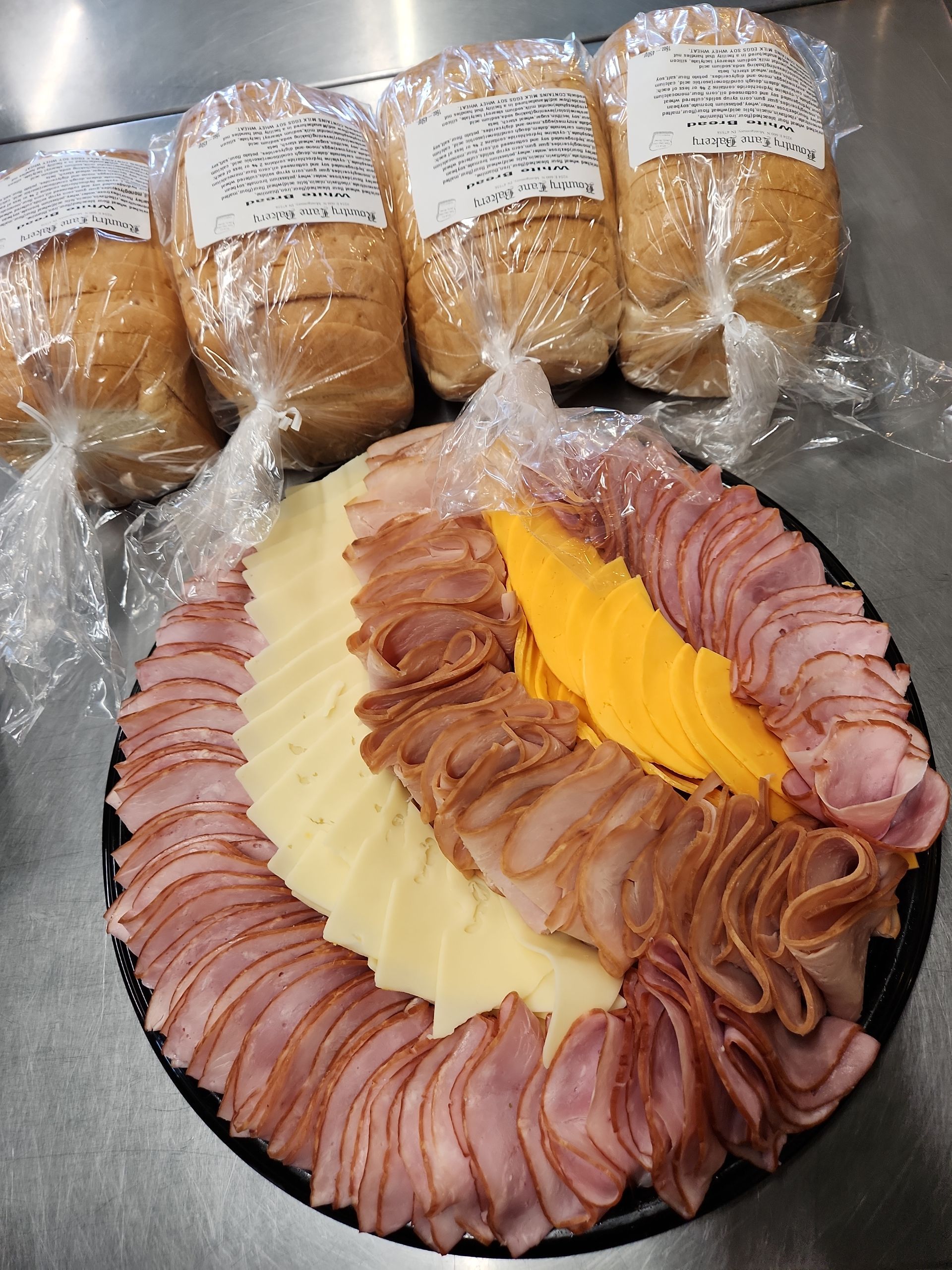 A plate of ham and cheese next to a bunch of bread