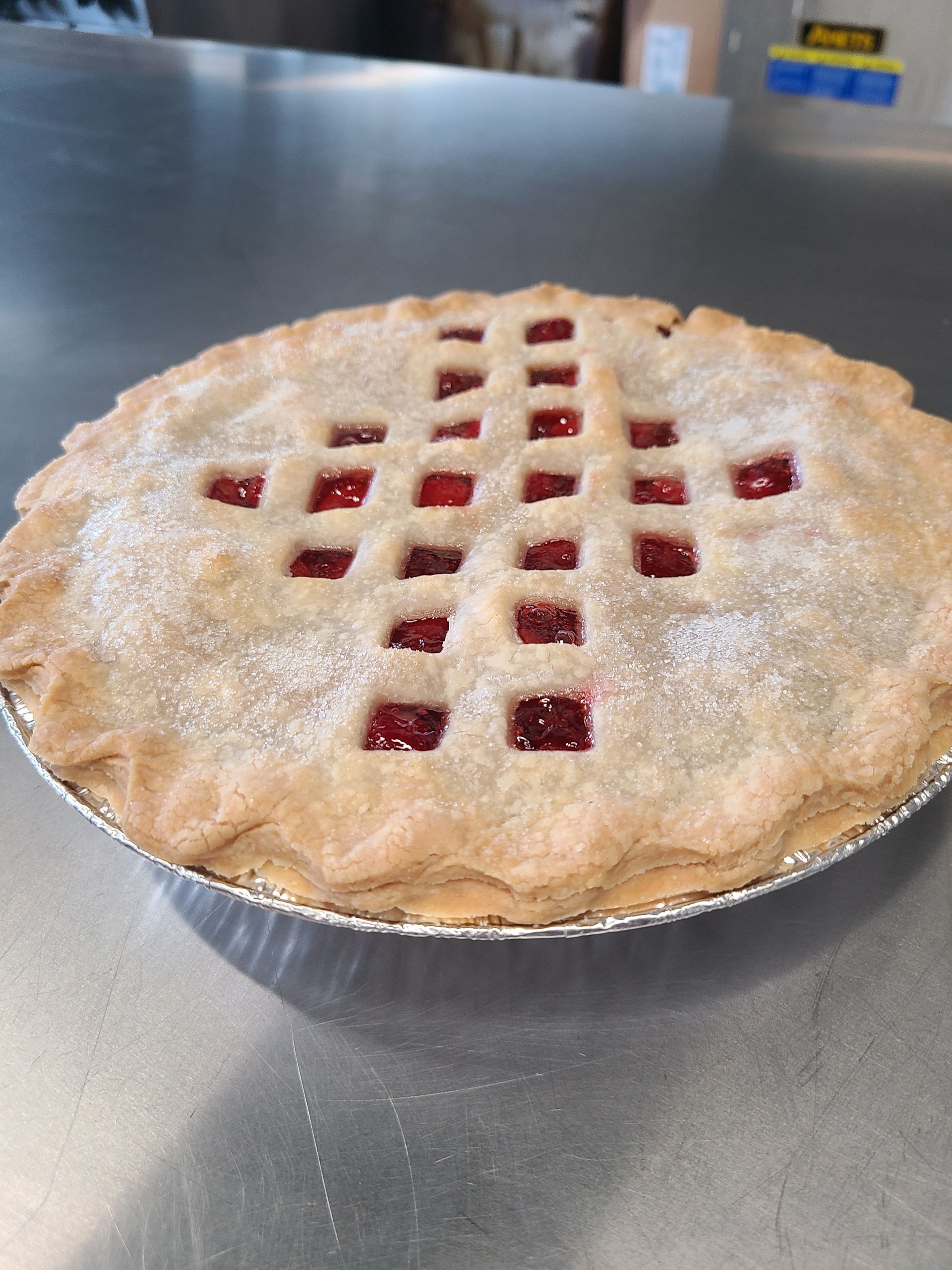 A strawberry pie is sitting on a metal table.