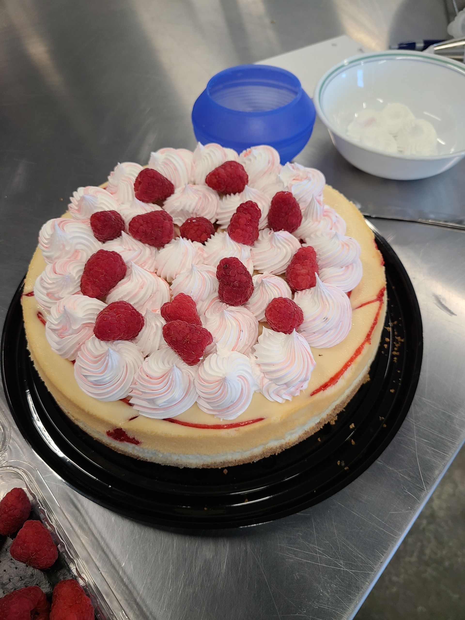 A cheesecake with raspberries and whipped cream on top