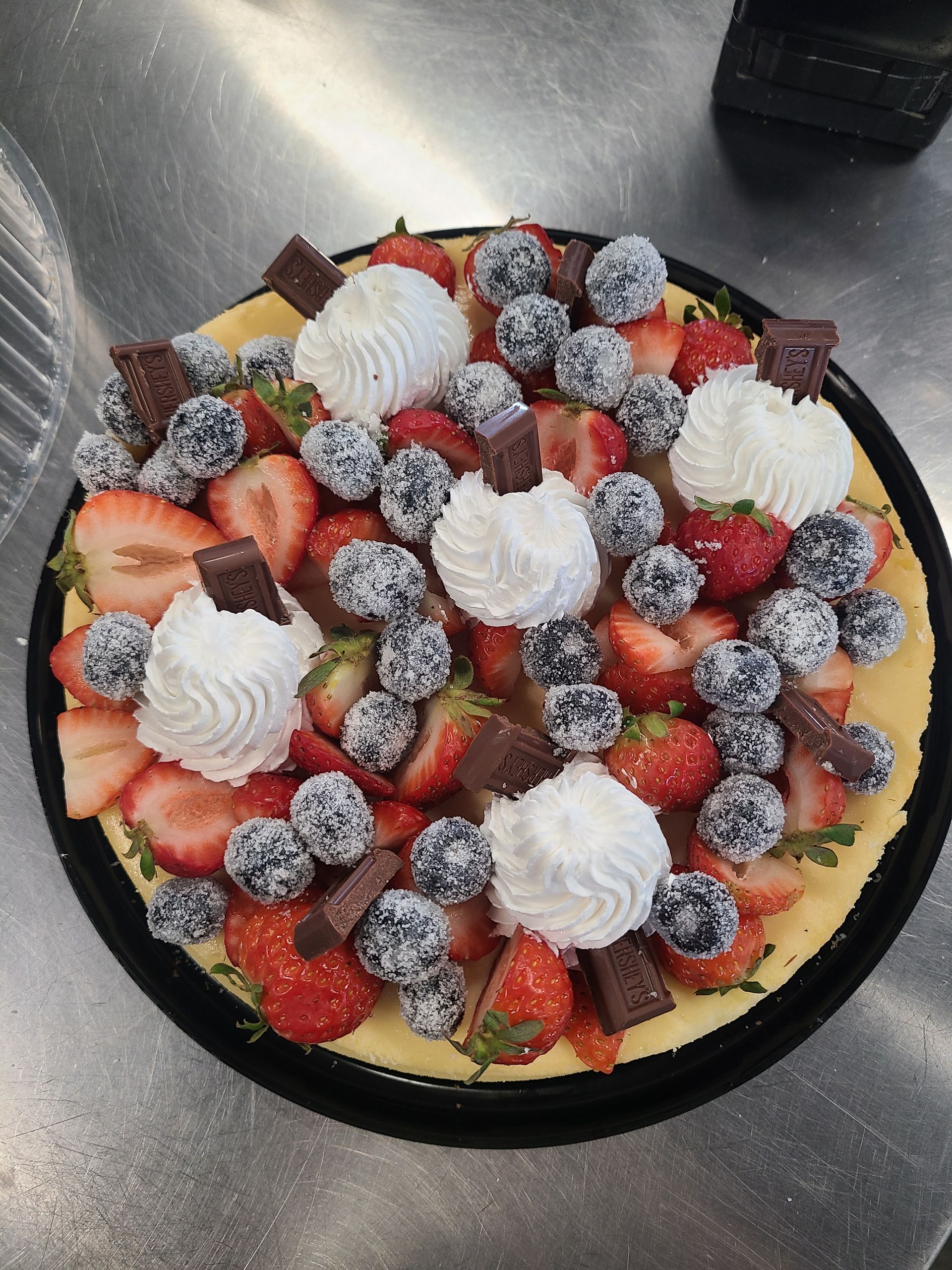 A pizza with whipped cream strawberries and blueberries on top
