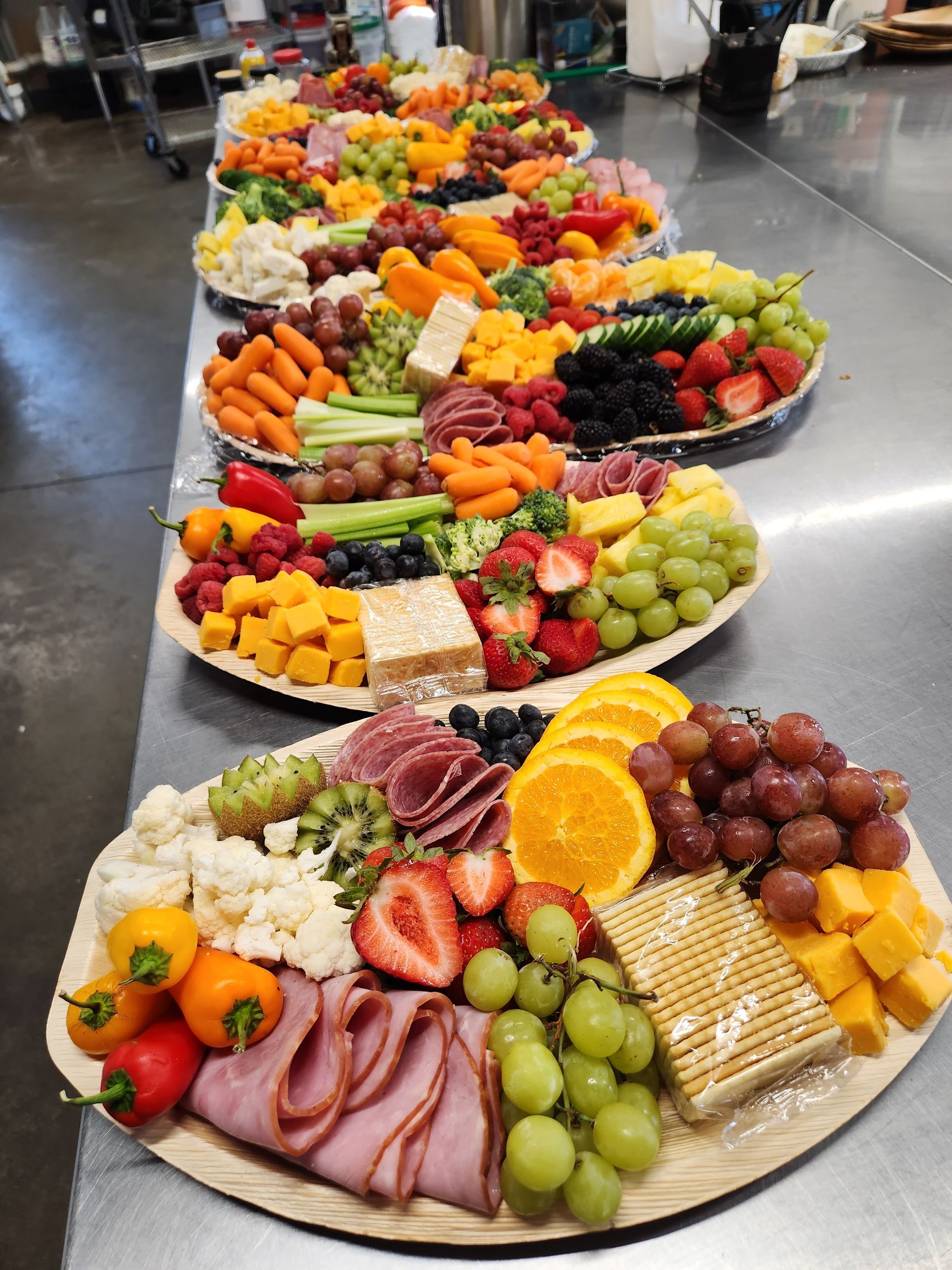 A row of trays filled with fruits and vegetables on a table.