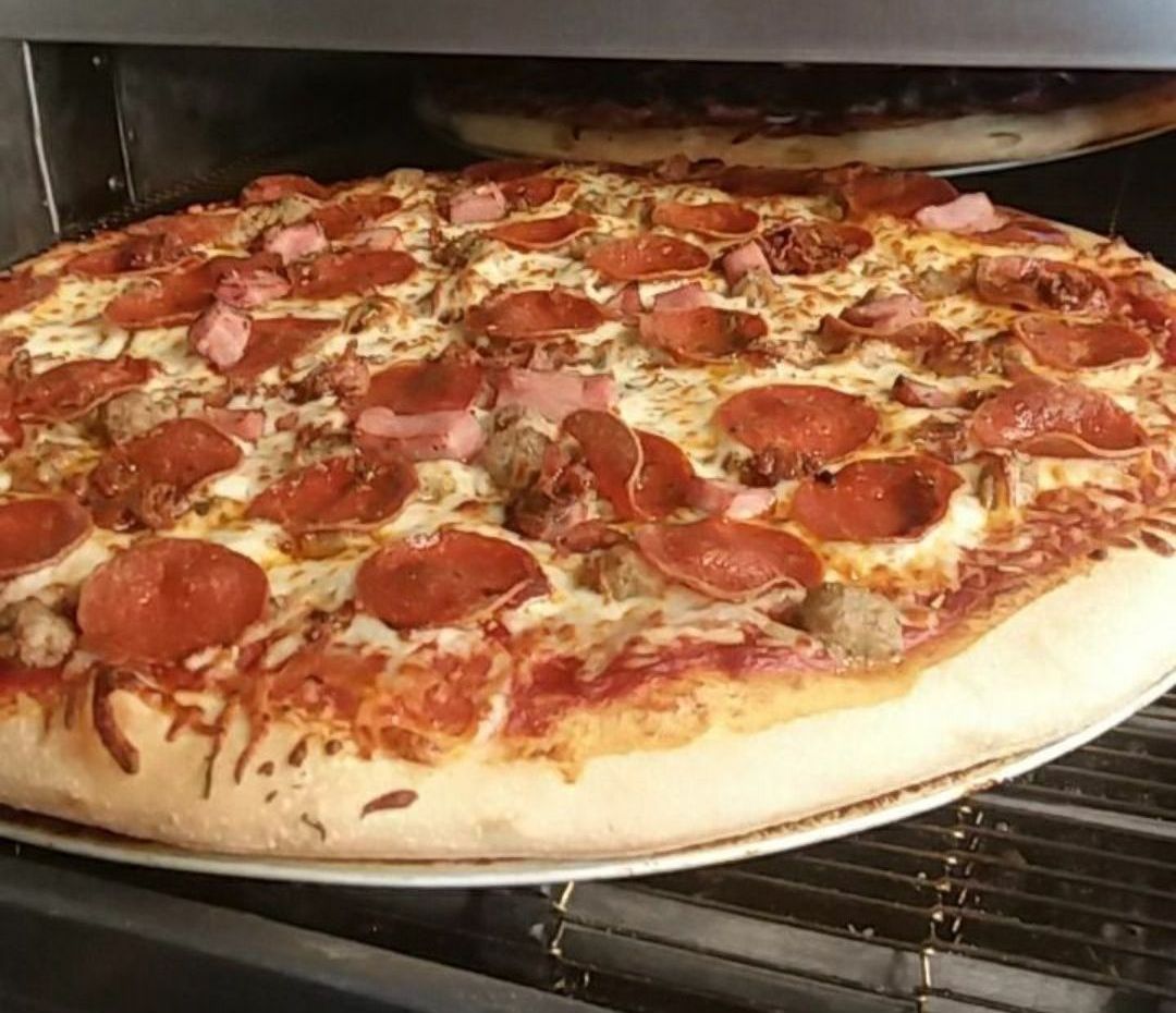 A pepperoni pizza is sitting on a pan in an oven.