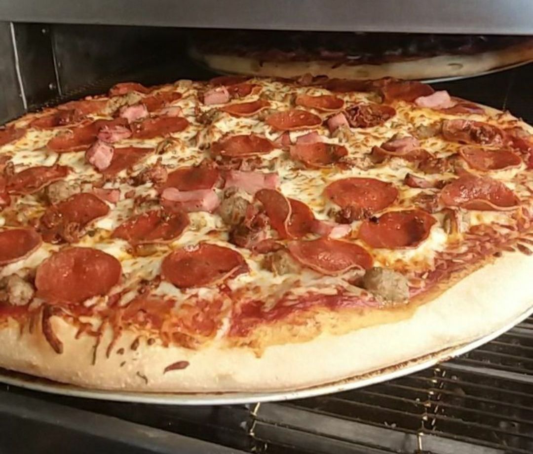 A pepperoni pizza is sitting on a plate in an oven.