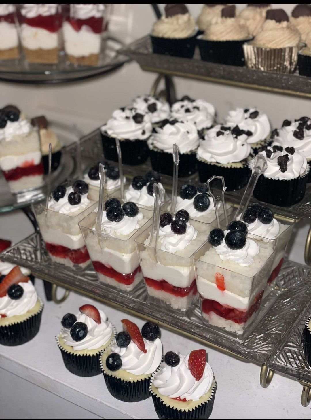 A tray of desserts including cupcakes and trifles