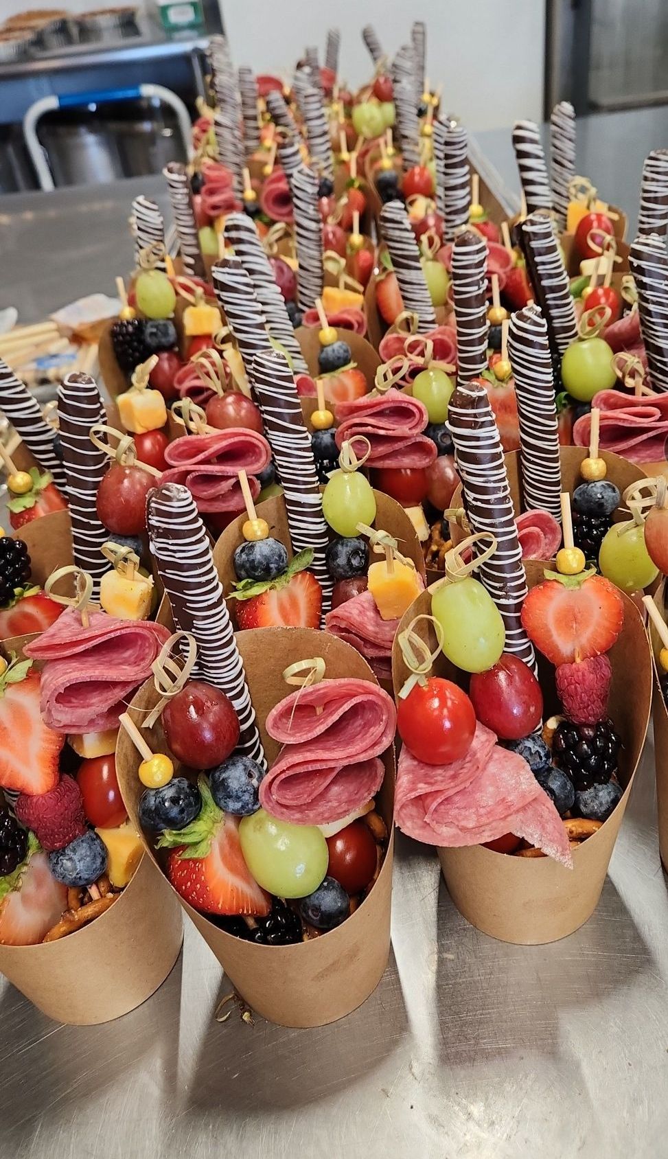 A bunch of cones filled with fruit and meat are sitting on a table.