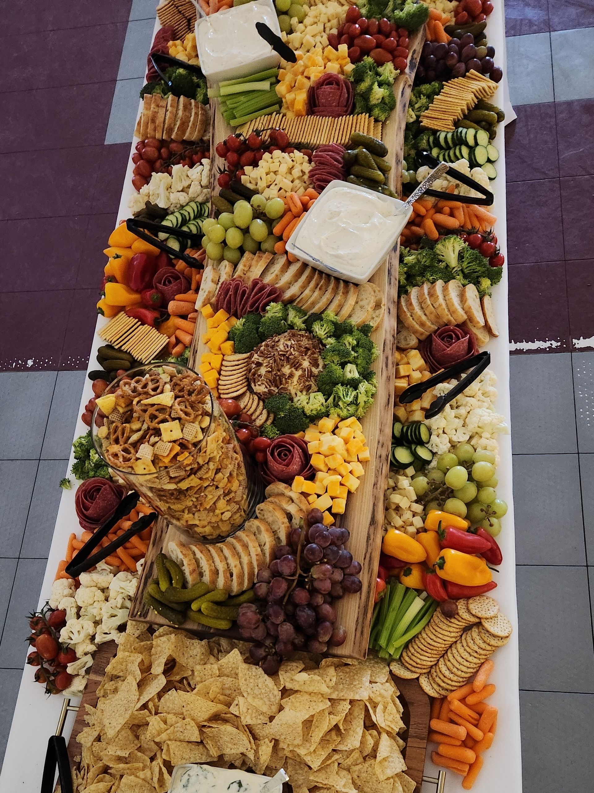 A long white table topped with a variety of fruits and vegetables.