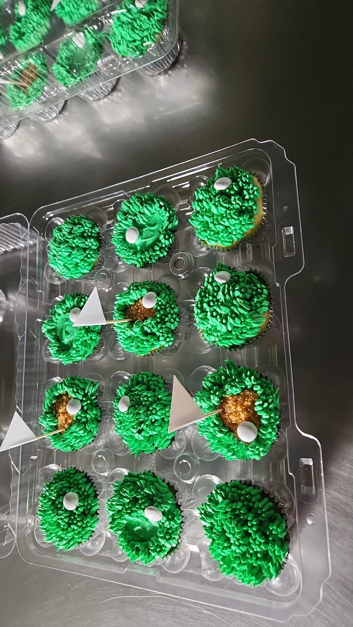 A tray of cupcakes with green frosting and sprinkles on a table.