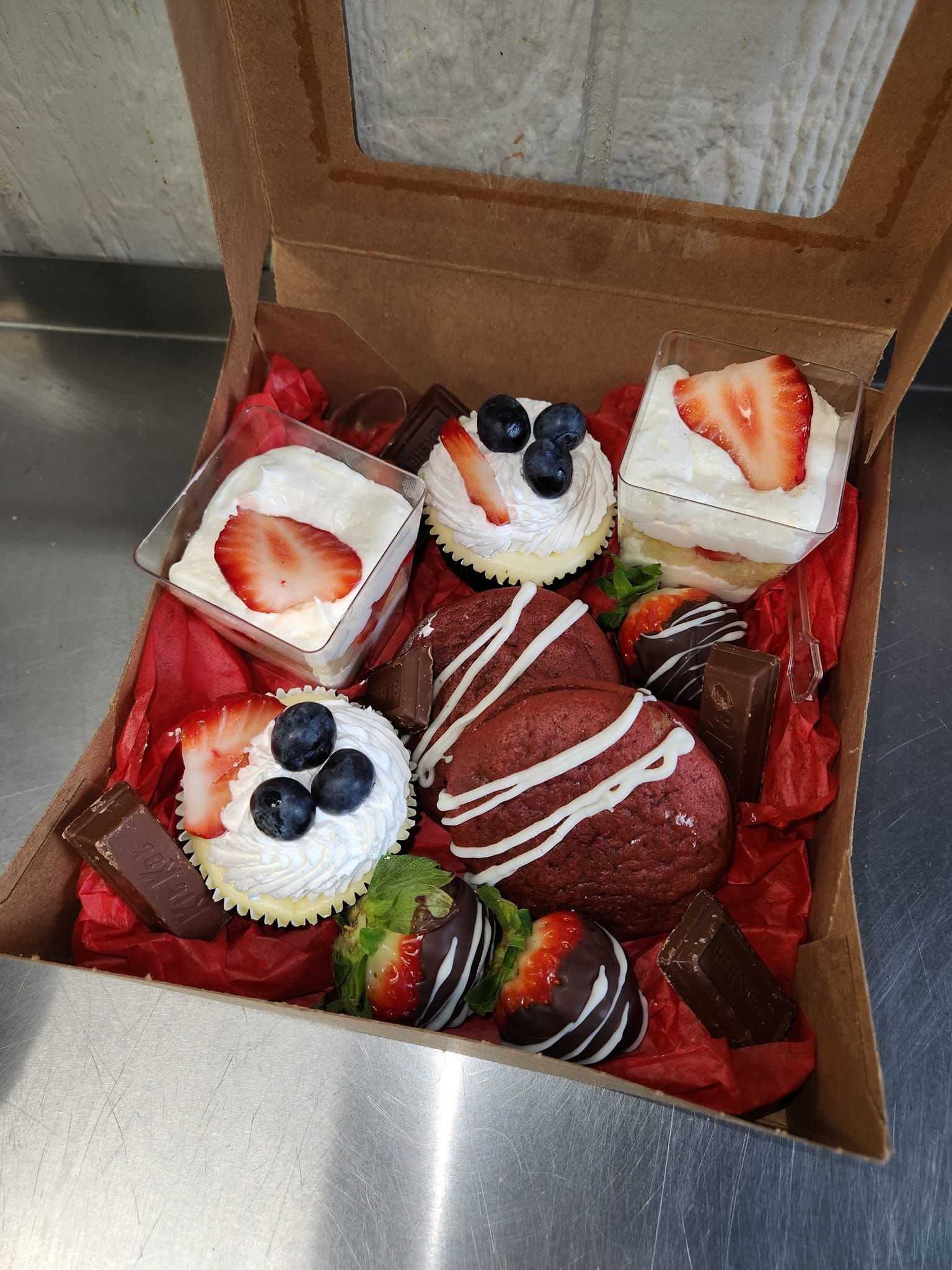 A box filled with cupcakes , strawberries , and chocolate covered strawberries.