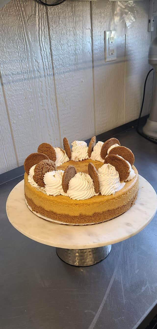 A cheesecake is sitting on top of a marble cake stand on a table.