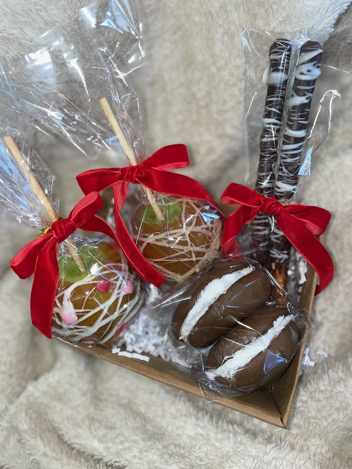 A box filled with caramel apples and chocolate covered pretzels.